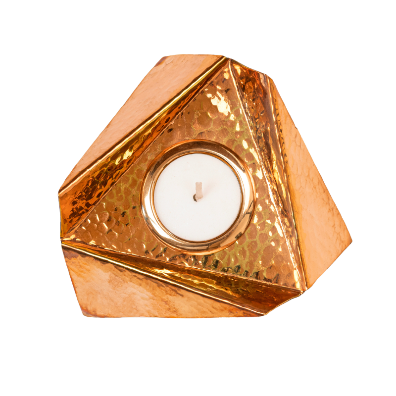 A copper plated brass Origami Tealight holder with a hammered texture and a candle inside, reflecting on the copper surface.