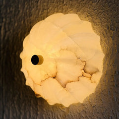 Side look of Spiral Alabaster Wall sconce, casting warm light with a textured surface on a dark background