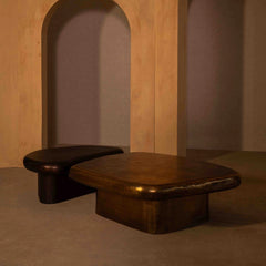 Two wooden coffee stools in a minimalistic room with an archway.