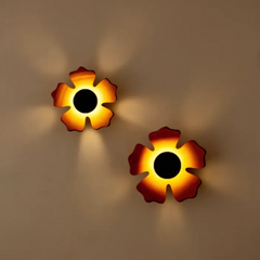 Two flower-shaped wall lights with warm glow on a beige wall.