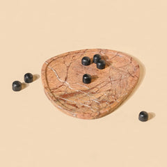 Marble-patterned trinket dish with black stones on a beige background