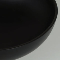 Close-up of a matte black bowl or planter rim against a light gray background.