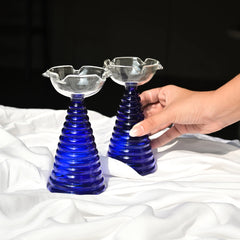2 stylish blue tall glass diya sets placed on white cloth