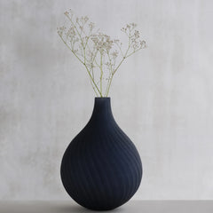 Dhara Black Vase made of glass with textured design, decorated with dried flowers on a light gray background