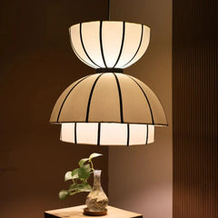 Aluna C Two-tiered pendant lamp with a vase and plant on a wooden surface