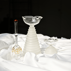 Tall glass diya with white ribbed pattern in bottom along with short diya and glass ringing bell 