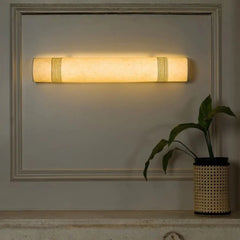 Wall-mounted light fixture on a wall with a plant in the corner