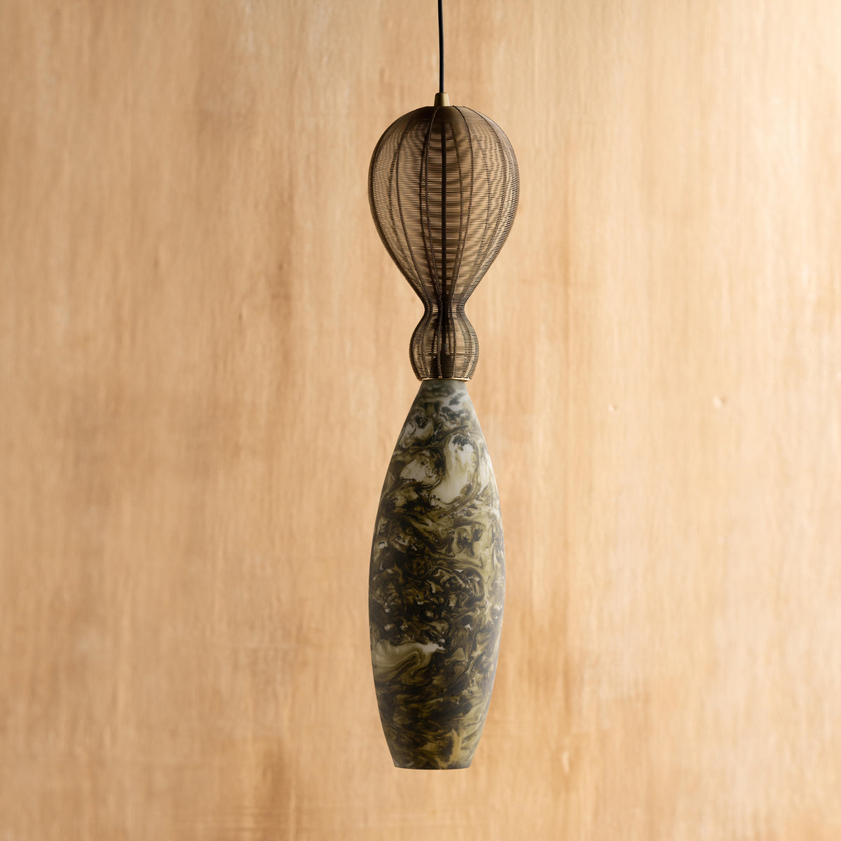 A green oval hanging lamp with a marble pattern, crafted from glass and mild steel, suspended against a wooden background.