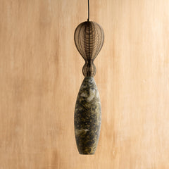 A green oval hanging lamp with a marble pattern, crafted from glass and mild steel, suspended against a wooden background.