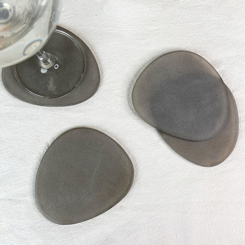 Brown Frosted Glass Coasters Set of 4 on a white surface with a glass of water