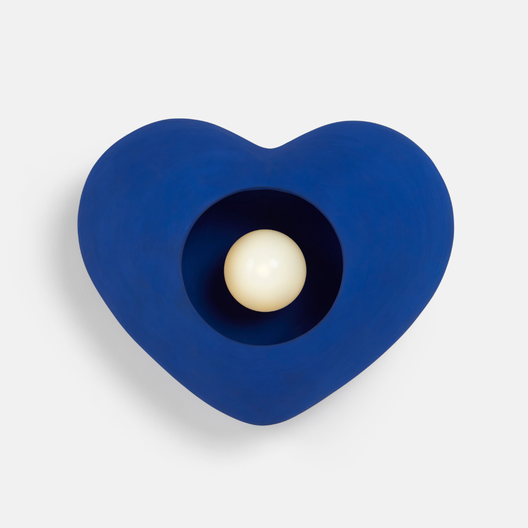 A heart-shaped blue wall light fixture with a white opal glass globe in the center, against a white background.