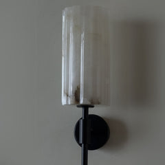 Wall-mounted light fixture with a Alabaster stone shade and black metal rod