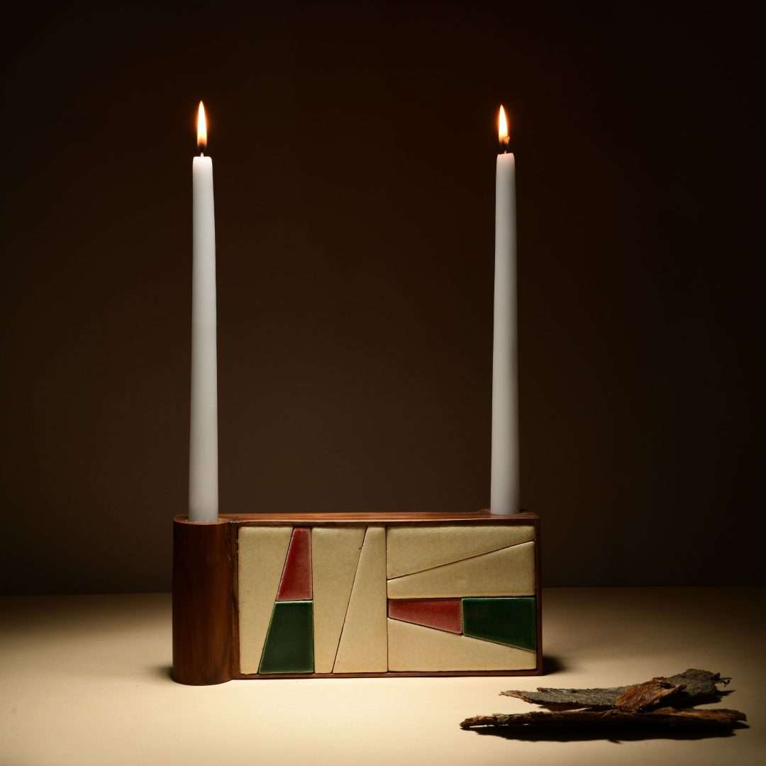 Tea Rose Candle holder with two lit candles on a dark background
