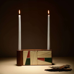Tea Rose Candle holder with two lit candles on a dark background