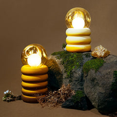Two decorative outdoor Honey Lume Table Lamps with glowing bulbs on a stone surface.