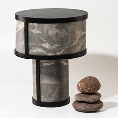 Unique cylindrical table lamp with a natural Indian Autumn slate base and a black powder-coated mild steel frame, accompanied by a decorative rock on a white background.