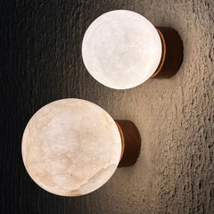 Two spherical white alabaster lamp wall sconces with dark brown wooden bases mounted on a textured dark gray wall.