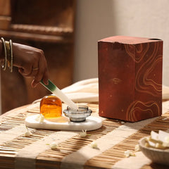 Muun Dome Tealight Holder in amber, tealight being lit in slate grey base with dome set aside, on white tray