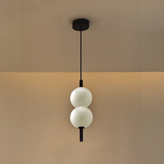 Modern pendant light with two white glass spheres on a beige background