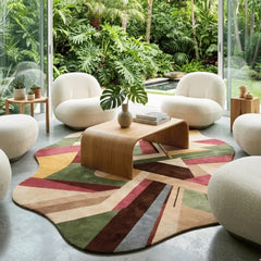 Modern living room with a colorful geometric rug, white chairs, and a wooden coffee table.