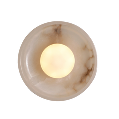 A wall sconce with a half round shade made of mottled white stone, with a visible light source within.