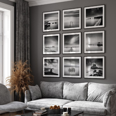 Black and white framed artwork 9 pieces on the wall with gray sectional sofa in a living room with