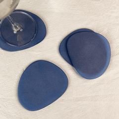Top view of blue frosted glass coasters, set of 4 placed on a table with a glass of water.