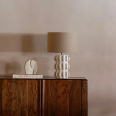 Spar Table Lamp with a textured base and brown shade on a wooden surface against a plain wall