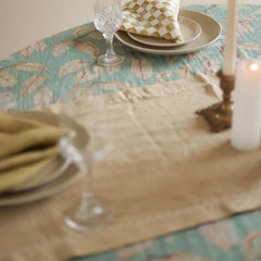 Mirage Sand Linen Table Runner across table with place setting and candle, angled view