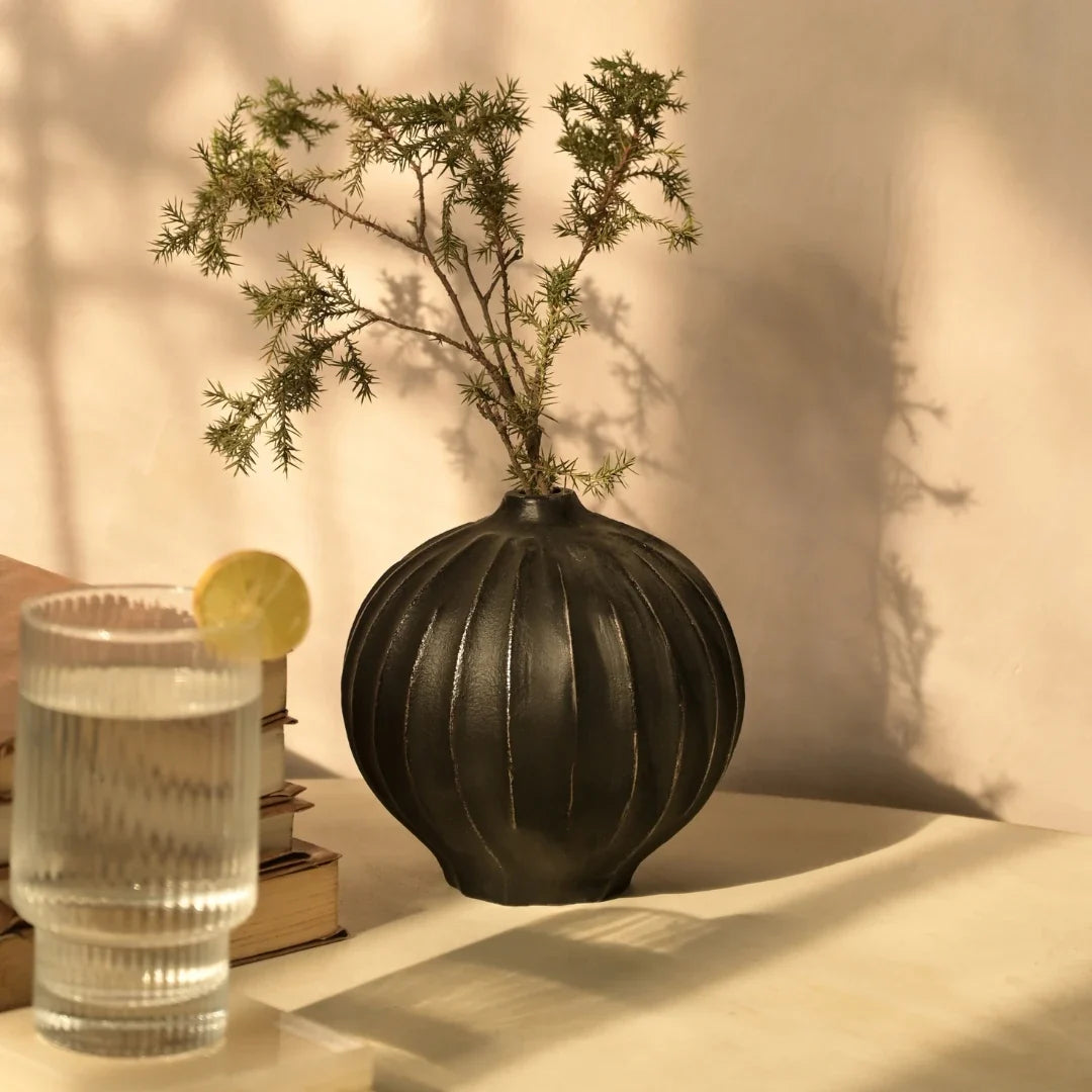 Unique Black textured Opus Vase with a glass of water and lemon slice.