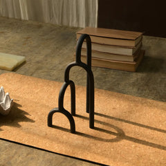 Black metal Aria Decor Sculpture on a textured surface with books in the background