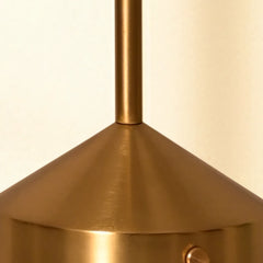Close-up of a gold Orbit Portable Lamp with a beige background