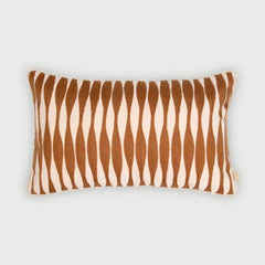 A rectangular throw pillow with a vertical wavy stripe pattern in warm brown and cream, shown against a neutral light gray background.