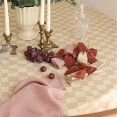 Solid bow shape Rhubarb Velvet Napkin Rings with brass candlesticks and grapes on checked cloth