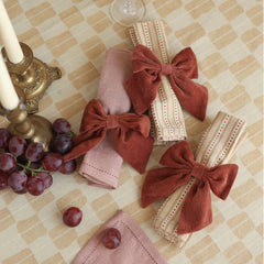 Solid bow shape Rhubarb Velvet Napkin Rings made of Cotton Micro-Velvet on pink and striped napkins.