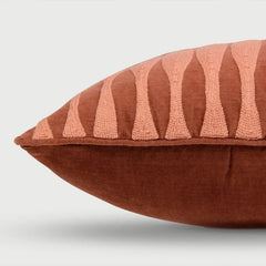 Brown pillow with pink geometric pattern on a light gray background