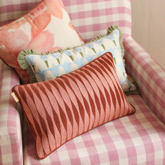 A pink and white checkered armchair with three decorative throw pillows in the foreground and background.
