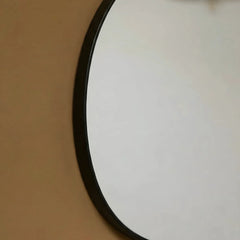 Close view of Round Pebble Mirror with black rim on a brown background