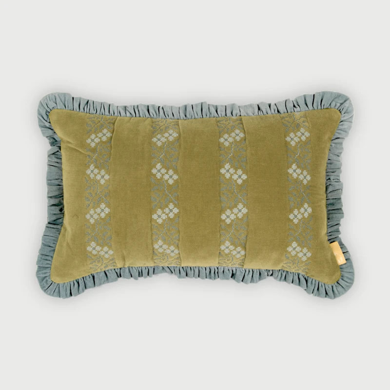 A rectangular decorative throw pillow with a ruffled border, featuring a muted olive green center panel with vertical white embroidered floral patterns and a dusty blue-gray ruffled trim, shown against a light gray background.