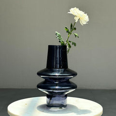 Black and clear Ripple Glass Vase with a white flower on a gray surface
