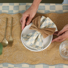 Sand Velvet Napkin Rings bow placed on checked napkin over quilted placemat, close view