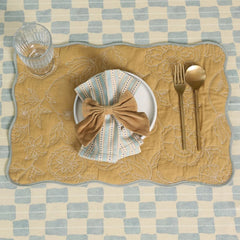 Sand Velvet Napkin Rings on striped napkin over scalloped quilted placemat, top view