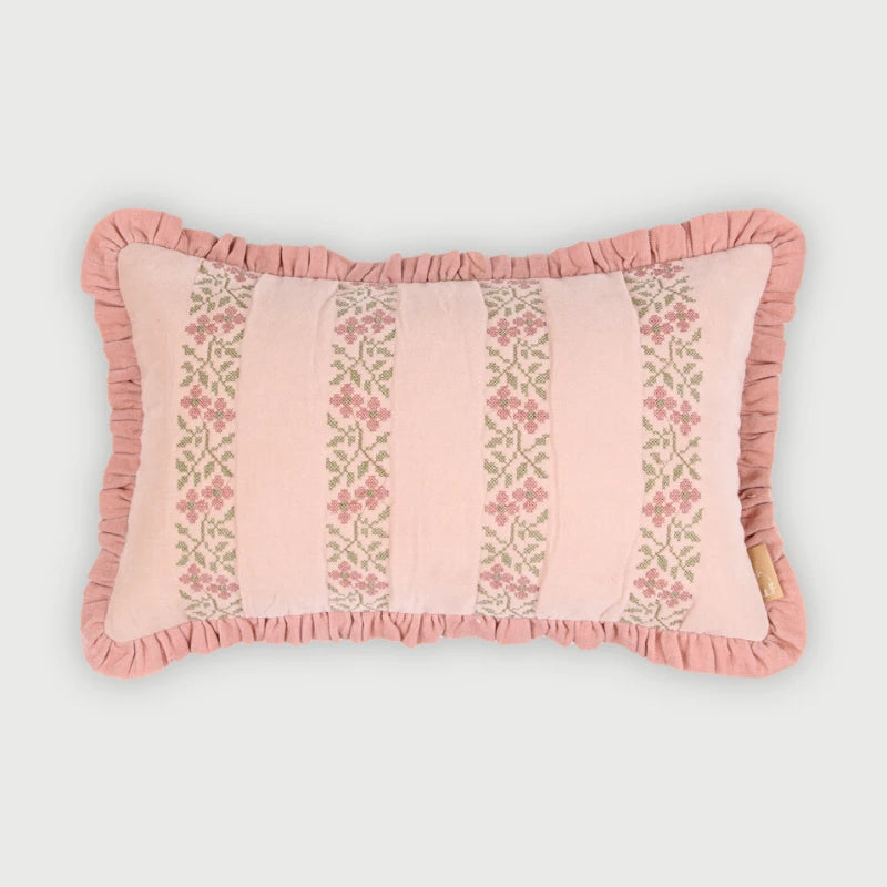 A rectangular pink decorative pillow with ruffled trim and vertical floral embroidered stripes, shown on a light gray background.