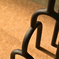 Close-up of a black metal Aria Decor Sculpture on a blurred brown surface