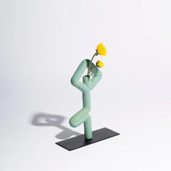 Sculptural vase in the shape of a person holding flowers on a white background