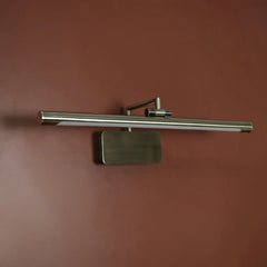 A modern wall-mounted light fixture with a long horizontal brushed metal bar, a rectangular backplate, and a small side adjustment knob, shown against a warm reddish-brown wall.