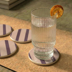 Clear glass with a lemon twist on a striped Rayè Coaster, surrounded by more coasters.