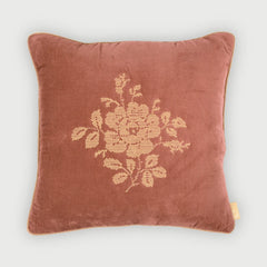 A square dusty rose velvet throw pillow featuring a beige embroidered floral motif in the center, set against a light gray background.