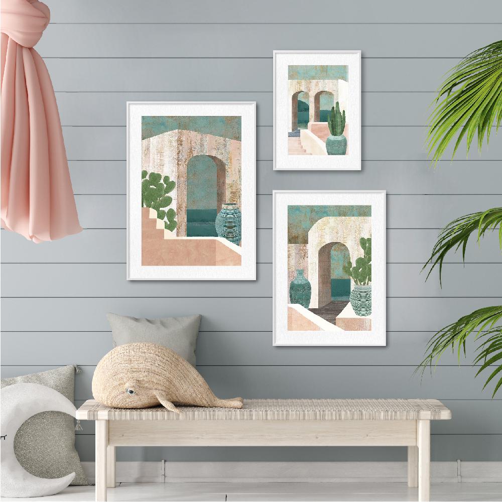Three framed art prints on a gray wall with a bench and decorative pillows below.