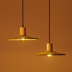 Two gold pendant lights with stripes against an orange background